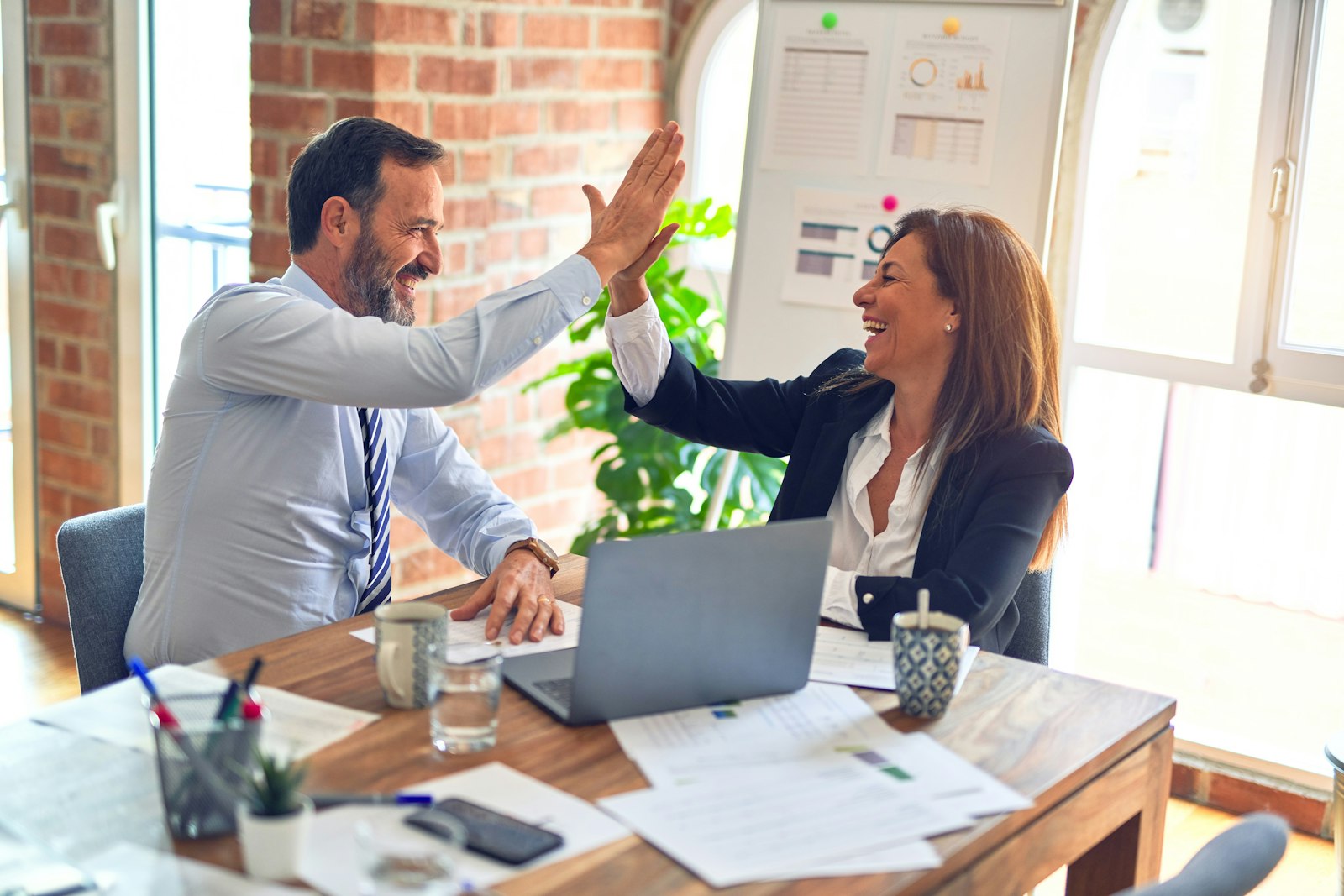 Polished local business owners celebrating a successful brand strategy session in a modern office