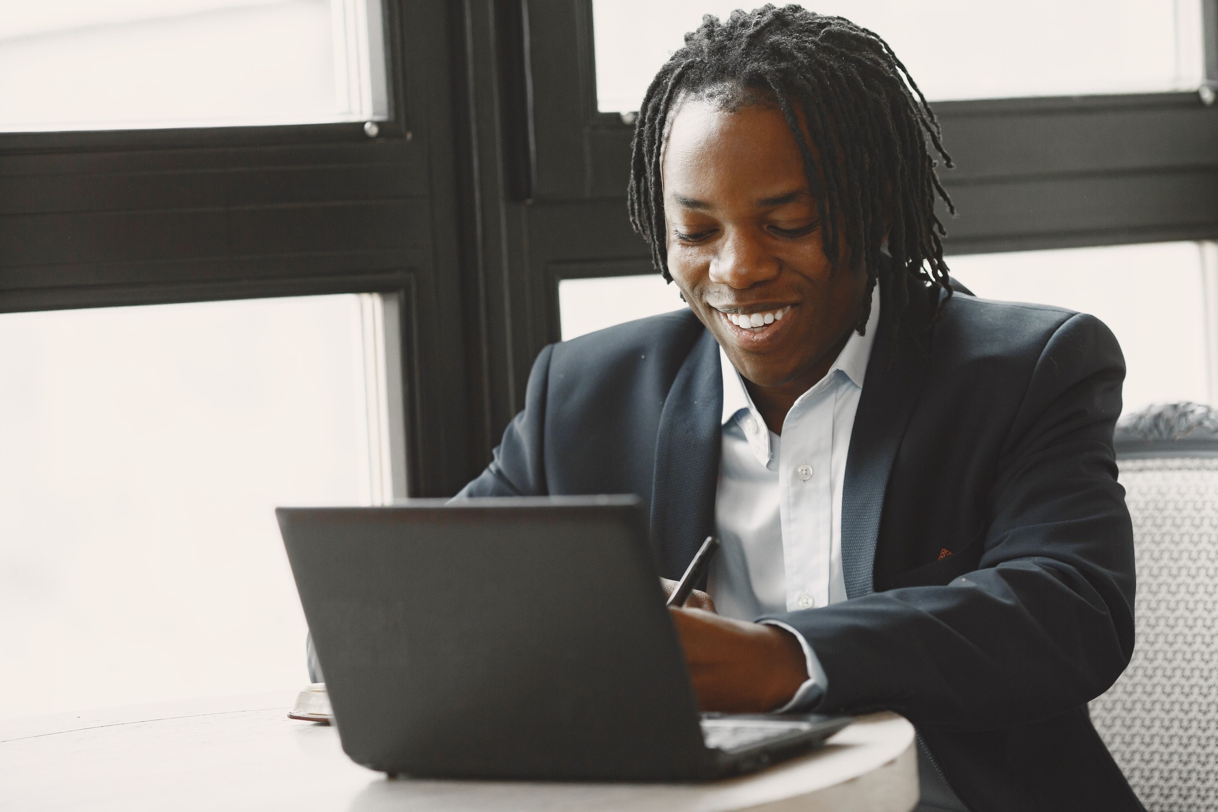 Smiling business owner in a blazer working on a laptop in a bright office, reviewing what Google shows for the business name and Knowledge Panel on mobile and desktop