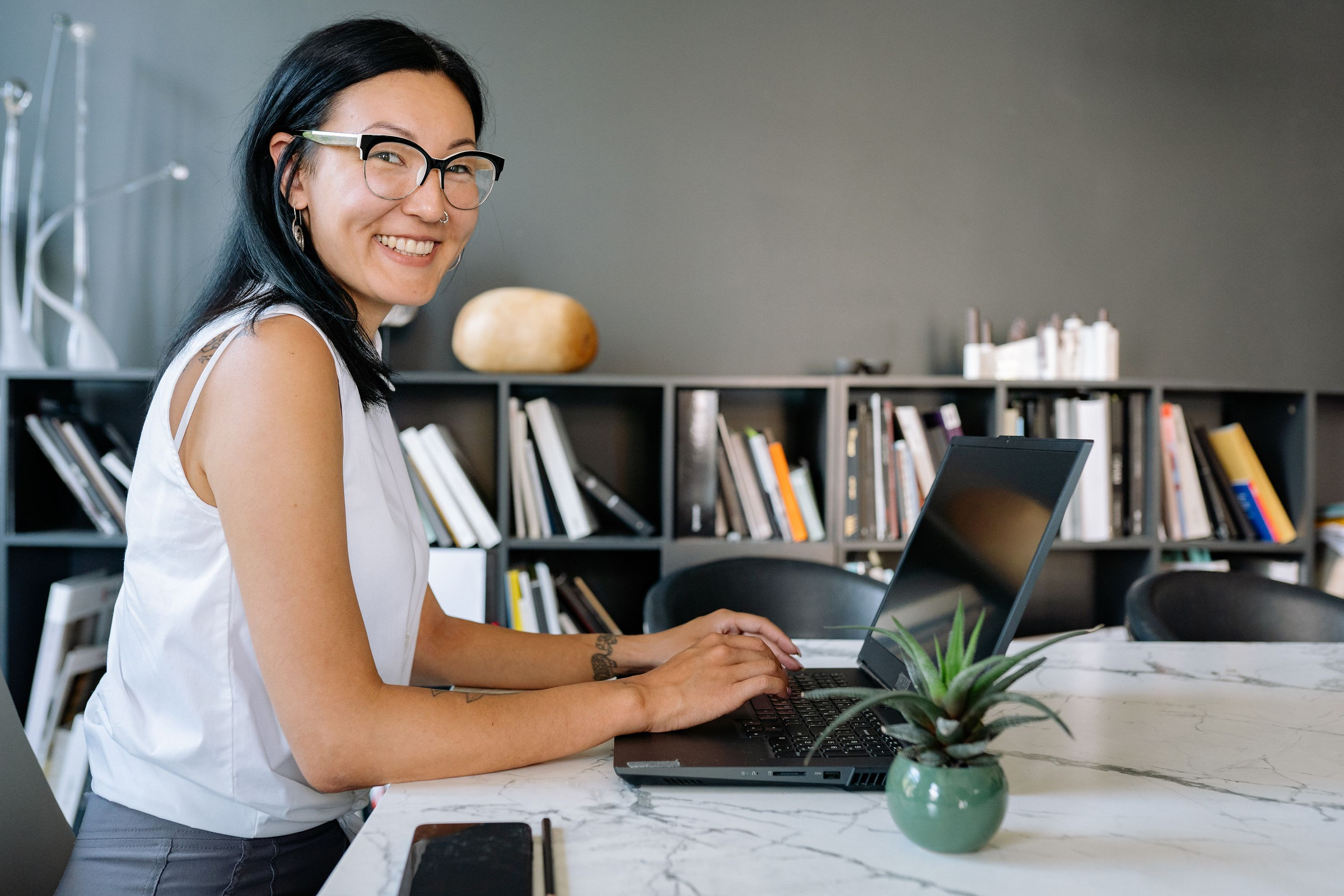 Smiling business owner with glasses at a marble desk with a laptop, reviewing Google Search Console multimodal and generative AI reports