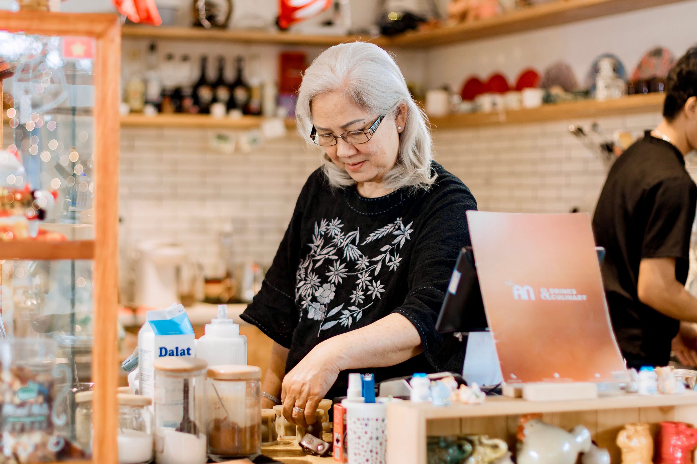 Shop owner in glasses working at her store counter