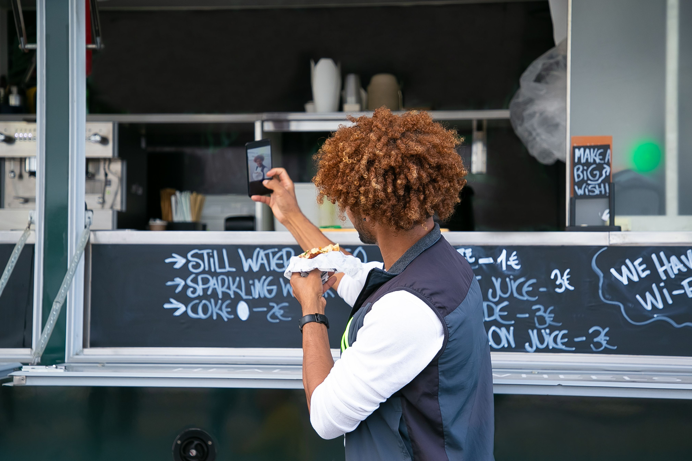 Food truck owner photographing his chalkboard menu with a smartphone so he can share it as a Google Business Profile post