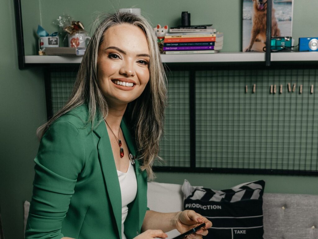 Polished, smiling local business owner in a green blazer checking Google reviews on her phone — Front-Row Reputation System