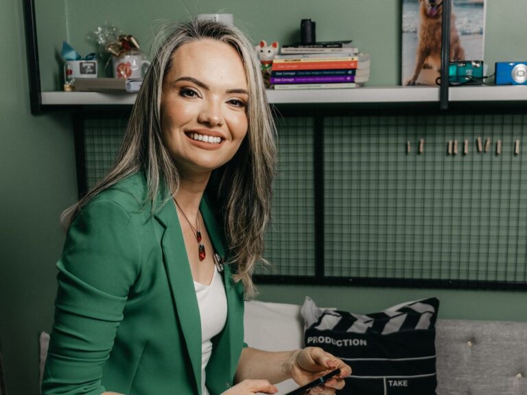 Polished, smiling local business owner in a green blazer checking Google reviews on her phone — Front-Row Reputation System