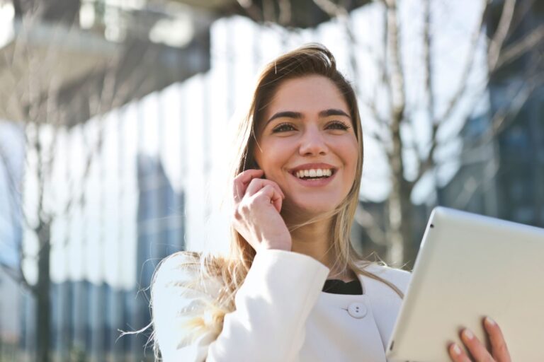 Polished business professional smiling on a phone call outdoors with tablet — AI call-readiness vibe
